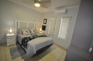 a bedroom with a bed with two lamps and two windows at The Bridge Apartments, Unit 34 in St Lucia