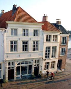 Une grande maison blanche avec des personnes debout devant elle dans l'établissement Hotel de Vischpoorte, hartje Deventer en aan de IJssel, à Deventer