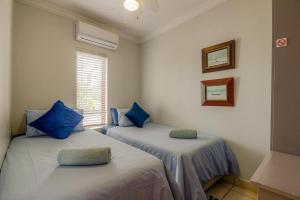 two beds in a room with blue pillows at The Bridge Apartments, Unit 34 in St Lucia