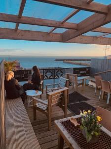 Harbour House Inn Newcastle, Northern Ireland في نيوكاسل: كانتا جالستين على سطح السفينة تطلان على المحيط