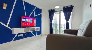 a living room with a tv on a blue wall at Cozzzzy Two Next to Axiata Arena, Bukit Jalil in Kuala Lumpur