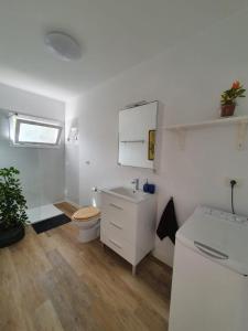 a white bathroom with a toilet and a sink at Cozy and intimate bungalow in Puerto de la Cruz in Puerto de la Cruz