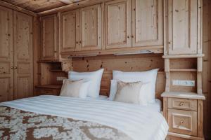 a bedroom with a white bed with wooden cabinets at Das Verwall - finest serviced apartments in Lech am Arlberg
