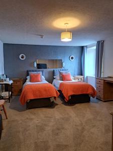 a bedroom with two beds with orange sheets at The Ship Inn in Bardsea