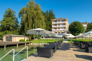 rzędu stołów i parasoli obok zbiornika wody w obiekcie Promenaden-Strandhotel Marolt Haupthaus w mieście Sankt Kanzian