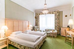 a bedroom with two beds and a chandelier at Hotel König von Ungarn in Vienna