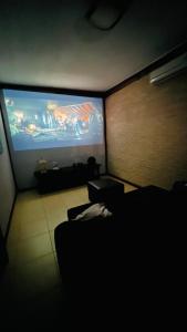 uma sala de estar com uma televisão de ecrã grande e um sofá em Conforto e Lazer é na Casa Bali em Ribeirão Preto