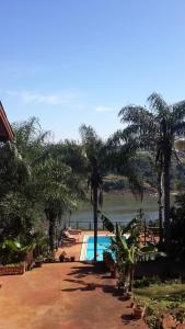 a resort with a swimming pool and palm trees at Stone Wall Cottages in Puerto Iguazú