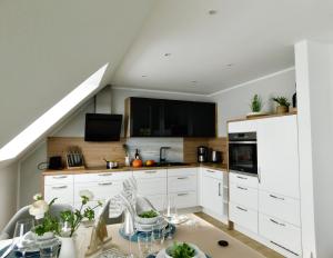 a kitchen with white cabinets and a table at Grachtensteern in Greetsiel