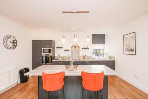 a kitchen with a large island with orange chairs at Mansfield Bar in Hawick