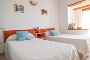 two beds in a room with white walls and blue pillows at Hostal Marblau Ibiza in Ibiza Town