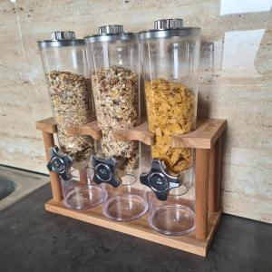 a display of four jars of granola on a wooden shelf at STUDIO 33 in Šabac