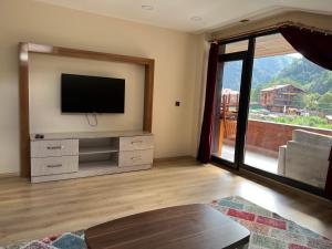 a living room with a television and a large window at Karadeniz Apart Otel in Uzungol