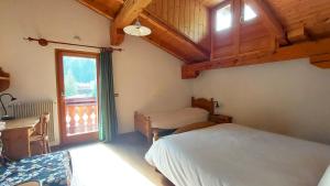 a bedroom with a bed and a desk and a window at La Sloda in Forno di Zoldo