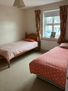 a bedroom with two beds and a window at Ballycastle, Strand Cottages Modern Home in Ballycastle