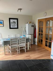 a dining room with a table and chairs and a refrigerator at Ballycastle, Strand Cottages Modern Home in Ballycastle +3 photos