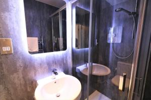 a bathroom with a sink and a shower with a mirror at Signature - Linden House Flat 1 in Airdrie +17 photos