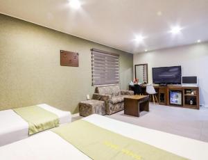 een hotelkamer met een bed, een bank en een tv bij Opera Motel in Yeosu