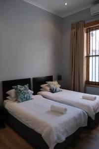 2 letti posti uno accanto all'altro in una camera da letto di Daddy Long Legs Self Catering Apartments a Città del Capo