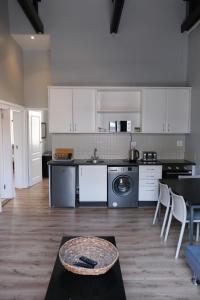 a kitchen with white cabinets and a table and chairs at Daddy Long Legs Self Catering Apartments in Cape Town