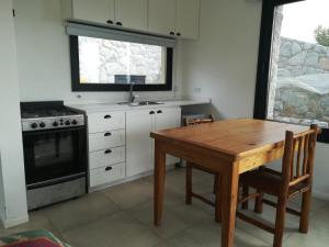 Loft en Rincon de la Cumbre في لا كومبر: مطبخ مع طاولة خشبية وموقد