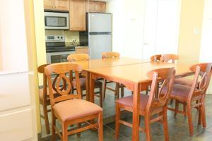 a kitchen with a wooden table with chairs and a refrigerator at Schooner II Beach and Racquet Club in Myrtle Beach
