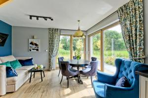 Una sala de estar con un sofá azul y una mesa y sillas. en Osada Białka Tatrzańska - apartamenty & domki z ogrodem dla rodzin Odkryj-Bialke, en Białka Tatrzanska