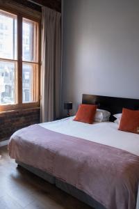 una camera da letto con un grande letto con cuscini arancioni di Daddy Long Legs Self Catering Apartments a Città del Capo