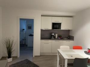 een keuken met witte kasten en een tafel met stoelen bij FlatDeCologne SunSet in Keulen