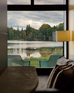 a room with a view of a lake through a window at PullanHouse Līksma - small and cosy lakeside holiday house in Alūksne