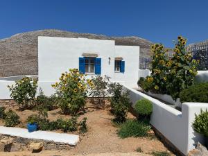 una casa blanca con una puerta azul y árboles en Cycladic houses in rural surrounding, en Amorgós
