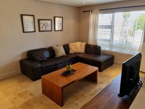 sala de estar con sofá de cuero y mesa de centro en Palm Zicht MAIN 3 bedroom apartment, en Ciudad del Cabo