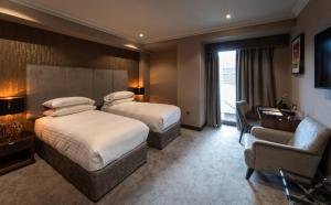 a hotel room with two beds and a chair at Ten Square Hotel in Belfast