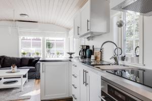a kitchen with white cabinets and a couch at Cozy mobile home near sandy beach in Hammar