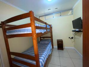 een slaapkamer met 2 stapelbedden en een televisie bij La casa de Ely in Iquique