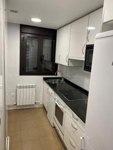 a kitchen with white cabinets and a black counter top at Casa Alberto 1 izda in Tudela +5 photos
