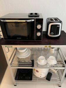a microwave sitting on top of a shelf with dishes at Patong Beach Gardens - Pool Fast WiFi Smart TVs in Patong Beach