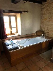 La salle de bains est pourvue d'une grande baignoire et d'une fenêtre. dans l'établissement Domaine Du Colombier, Gite La Renaissance, à Larroque