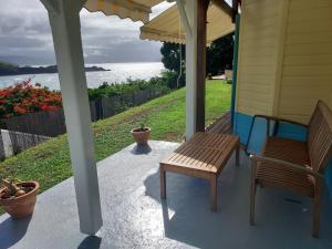 a porch with two benches on a house at la villa caribéenne de la plage des surfeurs in La Trinité