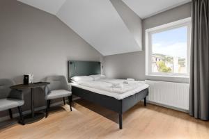 a bedroom with a bed and two chairs and a window at Forenom Serviced Apartments Drammen in Drammen