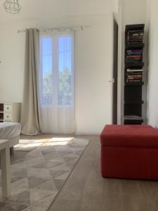 een woonkamer met een rode poef en een raam bij T2 proche du lac in Aix-les-Bains