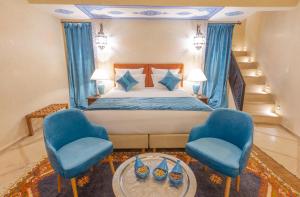 een slaapkamer met een bed en twee blauwe stoelen bij Riad El Hara in Marrakesh