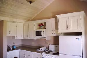 eine Küche mit weißen Schränken und einem weißen Kühlschrank in der Unterkunft Rustico Acres Cottages in North Rustico