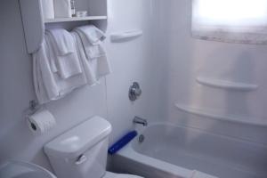 a white bathroom with a toilet and a bath tub at Rustico Acres Cottages in North Rustico