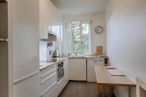 uma cozinha com armários brancos, uma mesa e um relógio em La Villa Normande - Trois Pièces - Deauville Centre em Deauville
