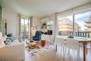 ein Wohnzimmer mit einem Tisch und Stühlen sowie einem großen Fenster in der Unterkunft La Villa Normande - Trois Pièces - Deauville Centre in Deauville