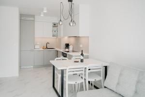 米兹多洛杰Norwida 17的白色的厨房，配有白色的桌子和椅子