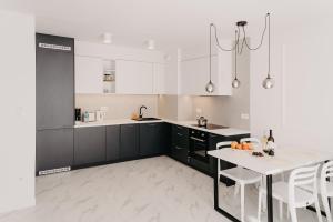 a kitchen with black cabinets and a white table at Norwida 17 in Międzyzdroje