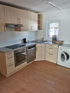 uma cozinha com um fogão, um lavatório e uma máquina de lavar roupa em Ferienwohnung ADAM im Haus Heidi em Höchenschwand