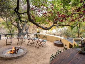 a patio with tables and chairs and a fire pit at Shimungwe Lodge in Hoedspruit